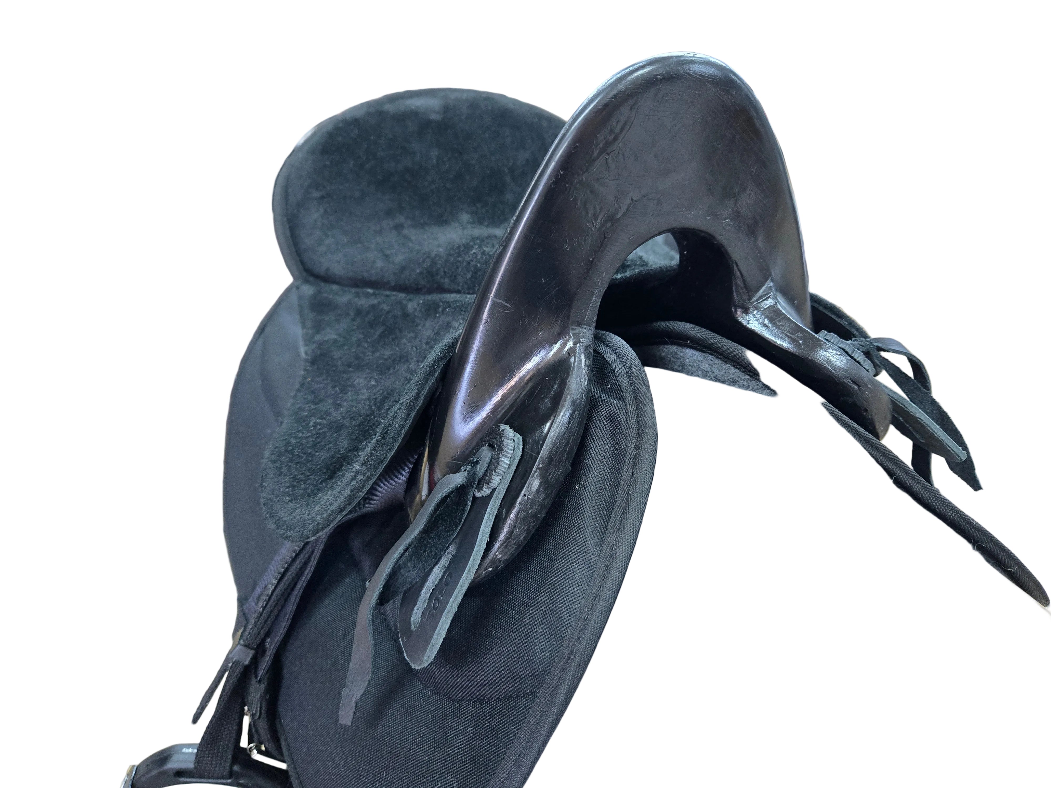 A close-up of a brown leather saddle with a black velvet saddle pad and black straps inside a retail store.
